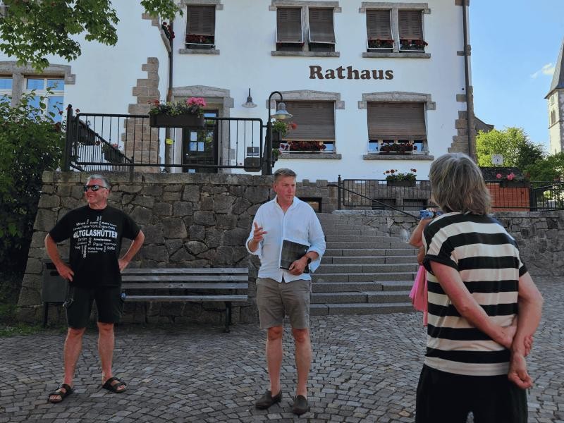 Die Teilnehmenden des Ortsteil-Dialogs stehen bei sonnigem Wetter auf dem Rathauspaltz in Altglashütten und diskutieren Zukunftspläne. Das Bild zeigt Bürgermeister Albrecht und Personen beim Ortsteildialog in Altglashütten vor dem Rathaus